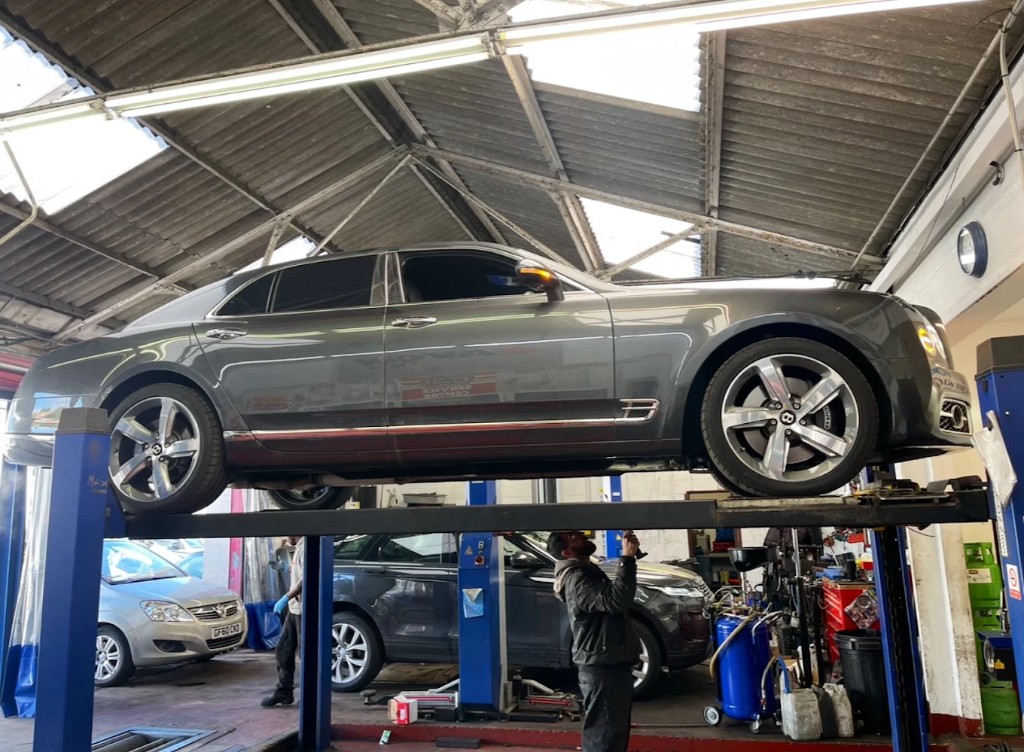 Mechanic working under a car on a four-post ramp